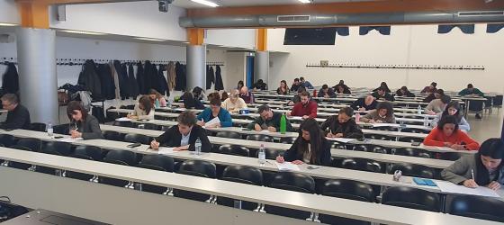 aula universitaria moderna, una decina di studenti e studentesse stanno scrivendo seduti alle loro postazioni
